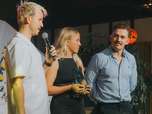 Winners on stage with their award, Ben Woolford on the mic